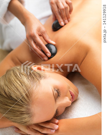 Woman, hot stone massage and spa with hands of masseuse, peace and treatment for destress at luxury resort. Serene, zen and calm with stress relief, self care and wellness with warm rocks for detox 141129918