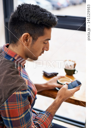 Man, coffee and typing with phone for social media, communication or networking at indoor cafe. Male person on mobile smartphone for online chatting, texting or app by window at cafeteria restaurant Man, coffee and typing with phone for social media, communication or networking at indoor cafe. Male person on mobile smartphone for online chatting, texting or app by window at cafeteria restaurant 141129983