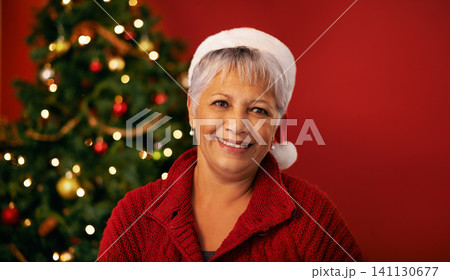 Christmas, smile and face of senior woman in studio for holiday celebration by tree isolated on a red background mockup space. Xmas, mature and happy female person in hat for festive season in Brazil Christmas, smile and face of senior woman in studio for holiday celebration by tree isolated on a red background mockup space. Xmas, mature and happy female person in hat for festive season in Brazil 141130677
