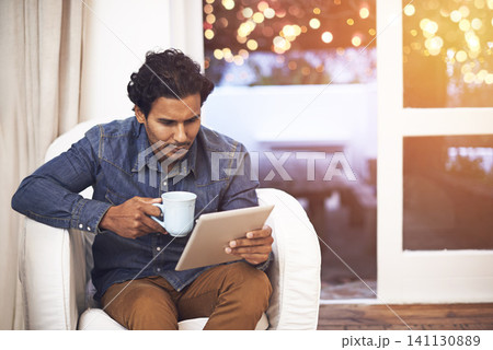 Tablet, coffee and man on sofa in living room for online blog on social media, app or internet. Reading, web and male person drinking cappuccino and scroll on digital technology in lounge at home. Tablet, coffee and man on sofa in living room for online blog on social media, app or internet. Reading, web and male person drinking cappuccino and scroll on digital technology in lounge at home. 141130889