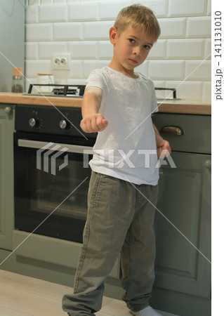 Little 7 years old kid boy practicing punches, karate, taekwondo movements at home. Athlete child practicing martial arts outdoors. Training in autumn day. Nature background. Dynamic Kyungkido. 141131010