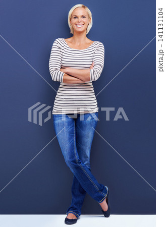 Portrait, arms crossed and happy woman in studio for fashion isolated on a blue background mockup space. Confidence, blonde and funny person in casual clothes or jeans on a backdrop in Switzerland 141131104