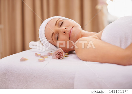 Woman, spa and rest for zen, wellness and peace with relaxation and calm. Lady, towel and massage table at resort, lounge or luxury parlor with rose for holistic body and skincare for detox and break 141131174