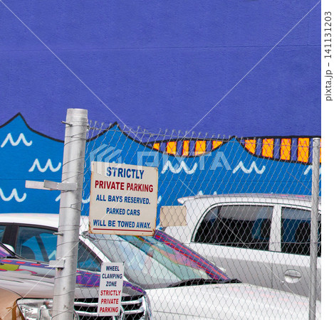 Road sign, warning and cars at private parking lot with information or graphic for design with transport. Board, security and outdoor with language for vehicle, attention and signage on fence in city 141131203