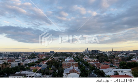 Scenic cityscape overview featuring low-rise houses and distant skyscrapers under colorful evening sky 141131487