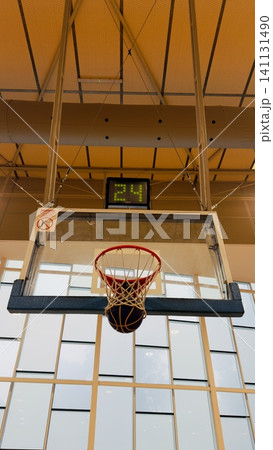 Game-winning point: Basketball in net with '24' second shot clock and warning sign, modern sports complex Game-winning point: Basketball in net with '24' second shot clock and warning sign, modern sports complex 141131490