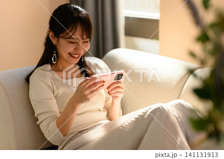 スマートフォンで動画を見る女性 スマートフォンで動画を見る女性 141131913