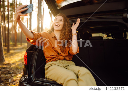 Woman is resting in trunk of car with phone. Concept of traveling by car, active lifestyle. 141132271