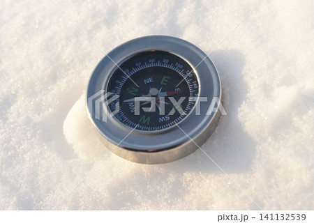 A shiny compass in the snow. Winter landscape of a traveler. A shiny compass in the snow. Winter landscape of a traveler. 141132539