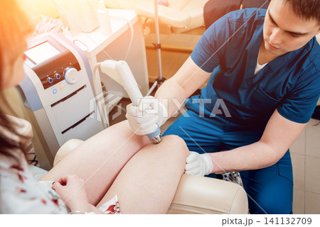 Shock wave therapy. The magnetic field, rehabilitation. Physiotherapist doctor performs surgery on a patient's knee 141132709