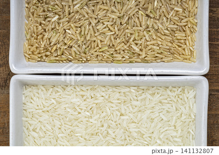 Brown and white jasmine rice (hom mali) in white plastic trays, close-up of uncooked rice grains, food ingredient for cooking, comparison concept Brown and white jasmine rice (hom mali) in white plastic trays, close-up of uncooked rice grains, food ingredient for cooking, comparison concept 141132807