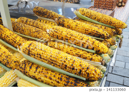 Golden corn cobs lined neatly at a bustling market stand Golden corn cobs lined neatly at a bustling market stand 141133060