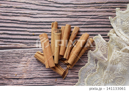 Cinnamon sticks lie elegantly on wooden surface with lace Cinnamon sticks lie elegantly on wooden surface with lace 141133061