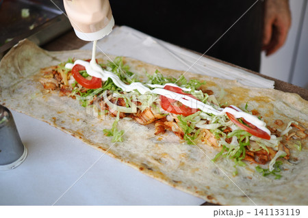Delicious wrap creation at a vibrant street food stall 141133119