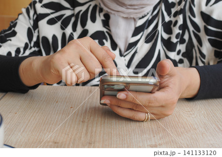 Engaging with a smartphone in a cozy cafe setting 141133120