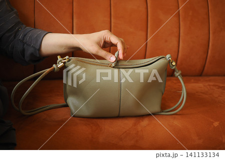 Elegant green purse rests on a cozy orange couch Elegant green purse rests on a cozy orange couch 141133134