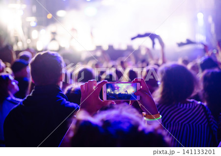 Holding a mobile phone in hands and shooting photo or video content. Youth, party, vacation concept. 141133201