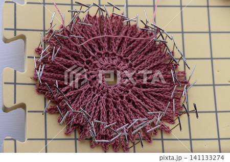 Hands shaping a crochet decorative piece during blocking Hands shaping a crochet decorative piece during blocking 141133274