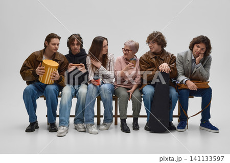 Multigenerational people waiting together with phones, drinks and personal items. Multigenerational people waiting together with phones, drinks and personal items. 141133597