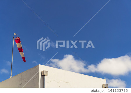 Red and white weather vane is on top of a building 141133756