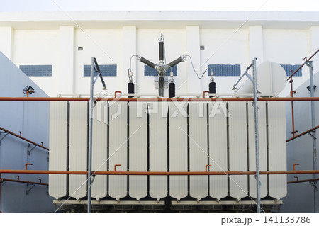A large power transformer with cooling fins and ceramic insulators at an electrical substation A large power transformer with cooling fins and ceramic insulators at an electrical substation 141133786