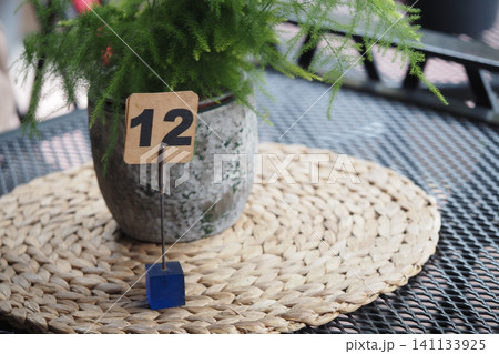 Table number 12 with plant in a pot on a woven mat Table number 12 with plant in a pot on a woven mat 141133925