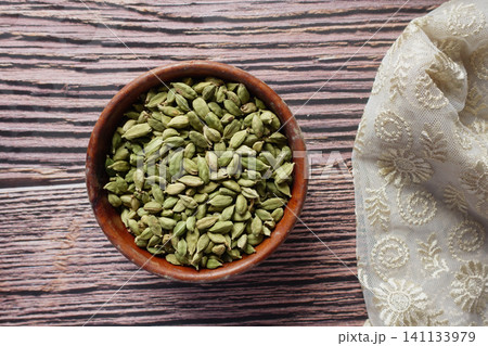 Bowl of green cardamom seeds on wooden table 141133979