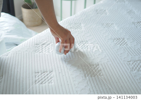 Person cleaning a mattress with a handheld device Person cleaning a mattress with a handheld device 141134003