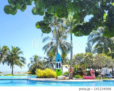 A pool with a green and blue surfboard leaning against a tree A pool with a green and blue surfboard leaning against a tree 141134098