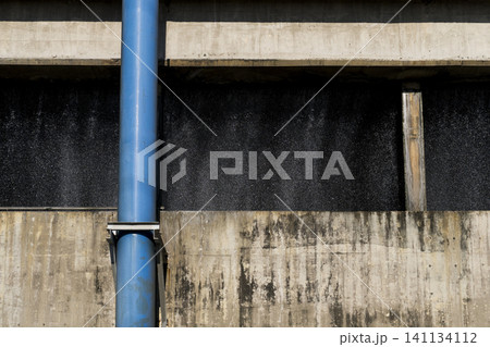 Close-up of cascading water droplets and a vertical blue pipeline inside an industrial cooling tower Close-up of cascading water droplets and a vertical blue pipeline inside an industrial cooling tower 141134112