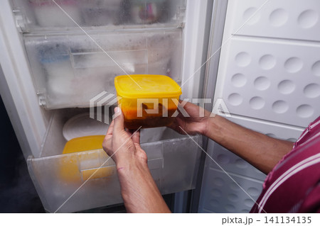 Person takes container from refrigerator Person takes container from refrigerator 141134135