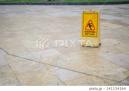 Caution sign alerts passersby to wet floor in public area Caution sign alerts passersby to wet floor in public area 141134164