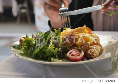 Enjoying a delicious meal with croissant and salad 141134204