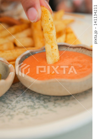 Fresh fries dipped in vibrant sauce at a casual eatery Fresh fries dipped in vibrant sauce at a casual eatery 141134211