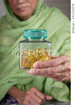 Elderly person holds a bottle of supplements in their hand Elderly person holds a bottle of supplements in their hand 141134216