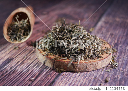 Herbal tea leaves on wooden surface in a calm setting Herbal tea leaves on wooden surface in a calm setting 141134358