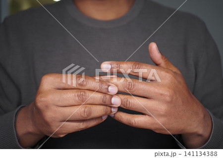 a young man hands close together, resembling gestures associated with pain or joint pain a young man hands close together, resembling gestures associated with pain or joint pain 141134388