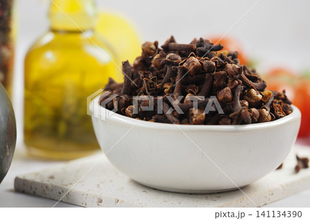 Cloves in a bowl with lemon and oil in the background Cloves in a bowl with lemon and oil in the background 141134390