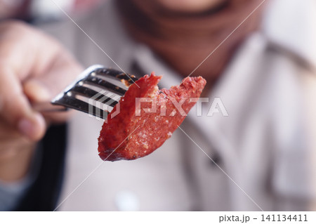 Deliciously prepared sausage on a fork during a meal 141134411