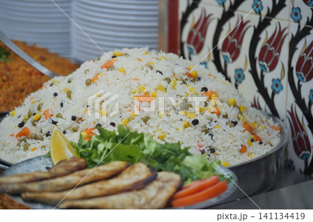 Rice dish with grilled fish on a silver platter at a market 141134419