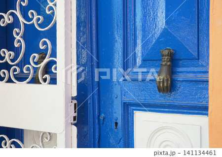 Blue door with hand knocker in vibrant scene Blue door with hand knocker in vibrant scene 141134461
