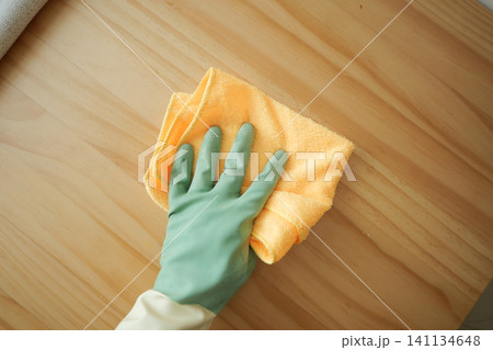 Person cleaning a wooden surface with cloth and gloves Person cleaning a wooden surface with cloth and gloves 141134648