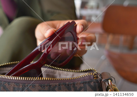 Stylish sunglasses being placed in a handbag after use 141134650