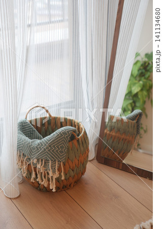 Basket near window with mirror and plant in indoor space Basket near window with mirror and plant in indoor space 141134680