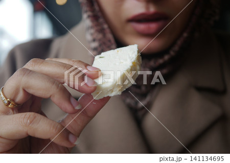 Woman holding a piece of cheese in a cafe Woman holding a piece of cheese in a cafe 141134695