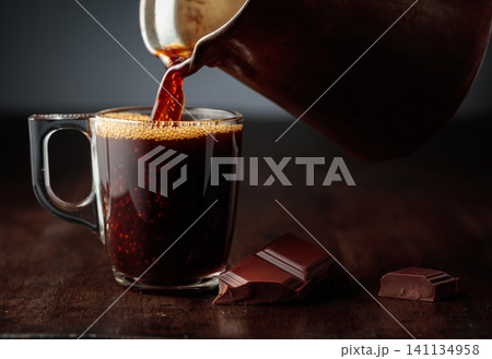Black coffee is poured into a glass cup. Black coffee is poured into a glass cup. 141134958
