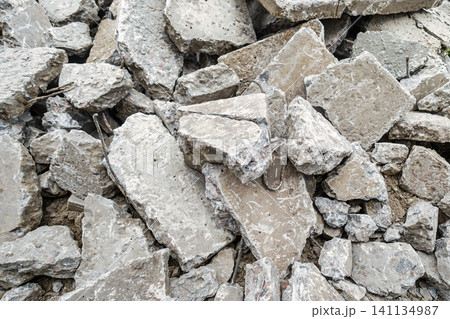 Broken concrete pieces are scattered on the ground at a construction site during the afternoon. Workers are preparing for new tasks nearby Broken concrete pieces are scattered on the ground at a construction site during the afternoon. Workers are preparing for new tasks nearby 141134987