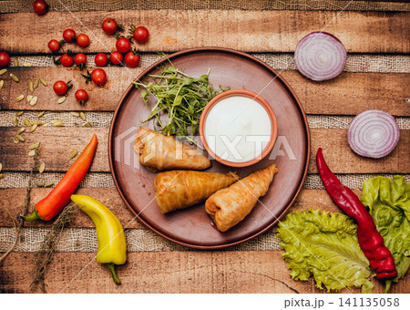 Tasty meat rolls with sour cream and salad on wooden table 141135058