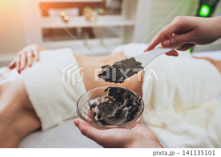 Beautiful woman in spa salon getting mud body massage Beautiful woman in spa salon getting mud body massage 141135101