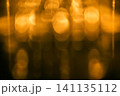 ガラスコップ越しに見えるロウソクの光をぼかした抽象背景 141135112